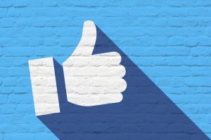 Facebook to eliminate ad set budget - blue background with white thumbs up
